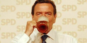 Gerhard Schröder trinkt eine Mass Bier, im Hintergrund steht an der Wand SPD