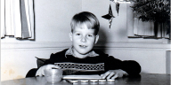 Junge sitzt mit Tuschkasten an einem Tisch