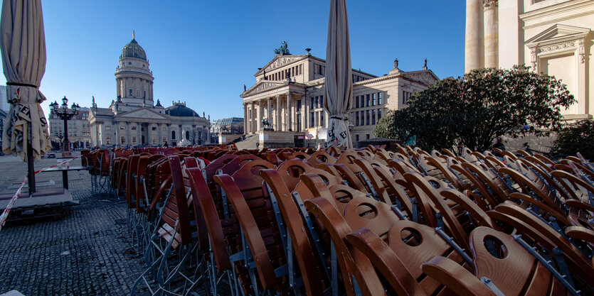 Viele Stühle von Restaurants stehen zusammen geklappt am Gendarmenmarkt in Berlin