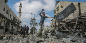 Ein Mann steht inmitten von Trümmern und räumt Trümmerteile weg