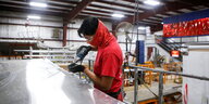 Arbeiter in roter Jacke vor einer Aluminiumplatte