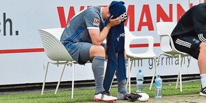 Toni Leistner vom HSV sitzt neben dem Spielfeld und hat sich einen Pulli über das Gesicht gezogen