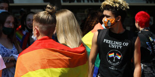 Menschen mit Regenbogenfahne bei einer Demonstration.