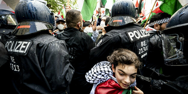 Polizisten stehen vor einer Gruppe demonstrierender Palästinenser