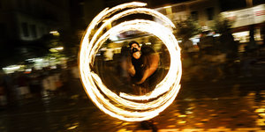 Artist jongliert mit Feuerstäben