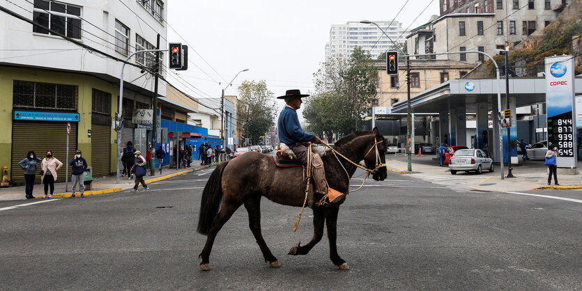 Ein Mann mit Hut reitet nach der Stimmabgabe in Valparaiso auf seinem Pferd über die Straße