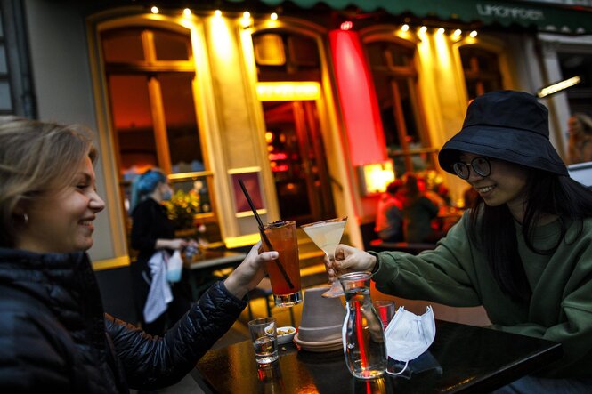 Menschen sitzen vor einer kneipe und trinken