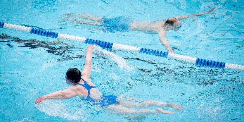 Zwei Menschen schwimmen im Schwimmbad