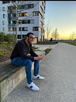 Leon Afen sitzt auf einer Mauer vor Hochhäusern Leon Afen sitzt auf einer Mauer vor Hochhäusern