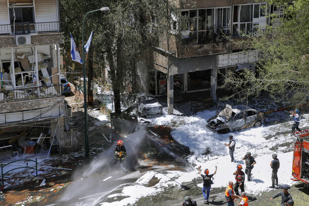 Feuerwehrleute löschen brendende Fahrzeuge vor einer zerstörten Hausfassade. Feuerwehrleute löschen brendende Fahrzeuge vor einer zerstörten Hausfassade.