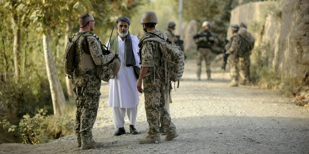 Ein Bundeswehrsoldat und ein Dolmetscher sprechen nahe Kundus im Distrikt von Char Darreh mit einem Mann.