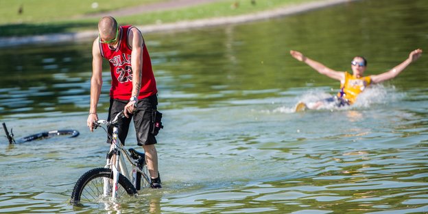 Mann fährt mit Rad durch einen Teich