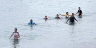 Junge Männer laufen durchs Wasser.
