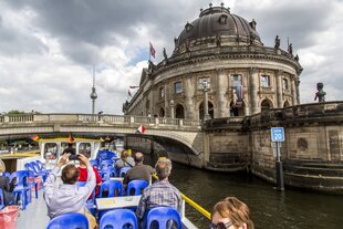 Das Foto zeigt ein Ausflugsschiff auf der Spree, das auf die Monbijoubrücke und das Bode-Musuem zufährt.