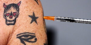 Spritze in einem tatowierten Oberarm