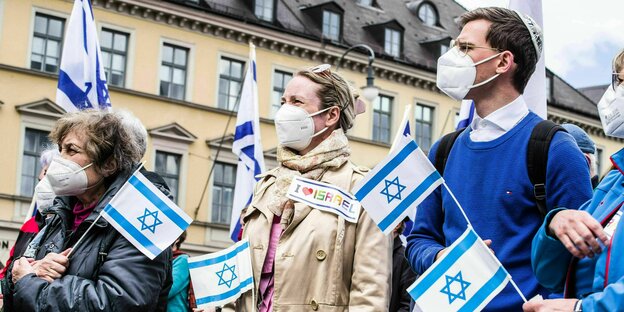 DemonstrantInnen mit Mundschutz und Israel-Fähnchen