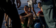 Zwei Männer sitzen am Strand von Ceuta, umringt von spanischen Sicherheitskräften