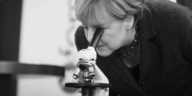 Bundeskanzlerin Merkel schaut durch ein Mikroskop.