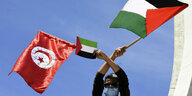 Eine Person mit tunesischer und palästinensicher Flagge.