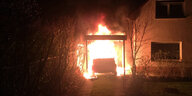 Ein lichterloh brennendes Auto in einem Carport neben einem Wohnhaus