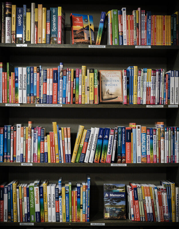 Bunte Buchrücken in einem Regal in der Reisebuchhandlung Schropp tragen Titel wie Spanien, Andalusien oder Menorca. Bunte Buchrücken in einem Regal in der Reisebuchhandlung Schropp tragen Titel wie Spanien, Andalusien oder Menorca.