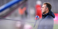 Bayern-Trainer vor einem Mikrofon mit verlängertem Arm