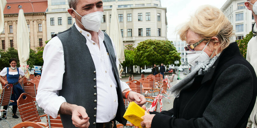 ein Frau zeigt dem Kellner ihr Impfheft