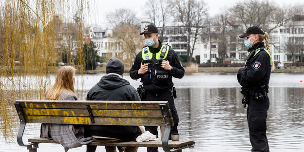 Wegen fehlender Mund-Nasen-Schutzmasken sprechen Polizisten an der Hamburger Außenalster ein Paar an