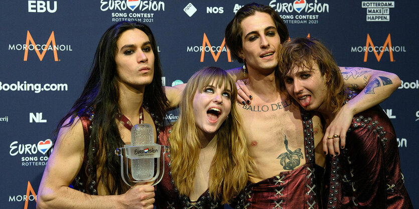 Die Musiker*innen von Maneskin stehen nebeneinander und präsentieren ihre ESC-Trophäe