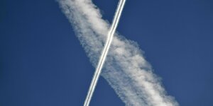 Zwei Kondensstreifen von Flugzeugen kreuzen sich im Himmel.