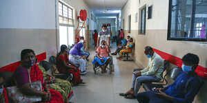 Wrtende PatientInnen in einem Krankenhaus in Indien - ein. Patient wird mit dem Rollstuhl geschoben