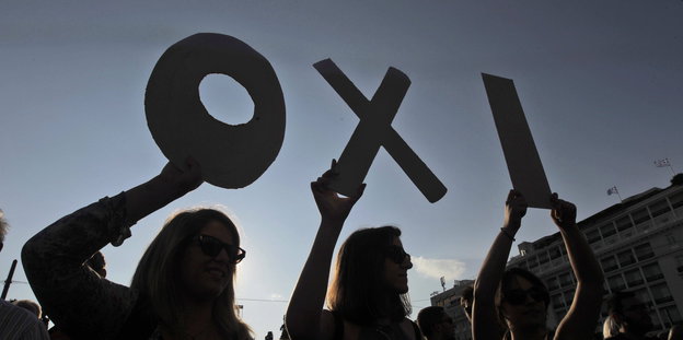 Vor der Abendsonne halten Menschen die Buchstaben des griechischen Wortes Oxi hoch
