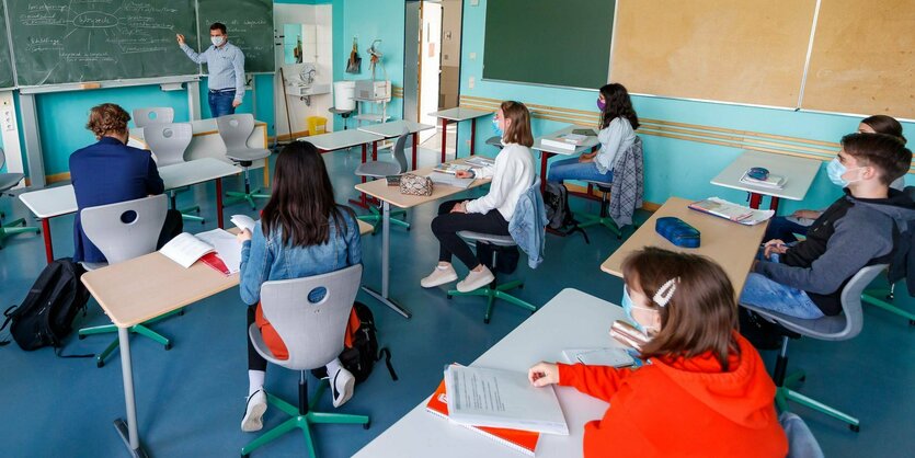 Zum Unterricht sitzen die Schüler verteilt mit einem Sicherheitsabstand im Klassenraum.