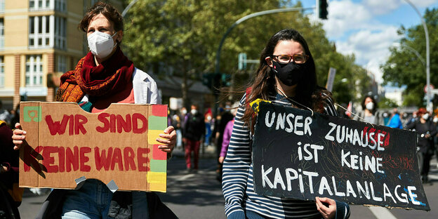 Zwei Frauen tragen Protestschilder: Wir sind keine Ware und unser Zuhause ist keine Kapitalanlage