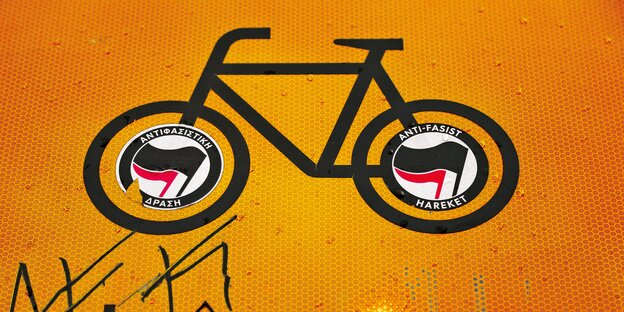 Ein Fahrrad-Piktogramm auf einem Boden. In den Reifen des Fahrrads kleben Antifa-Aufleber.
