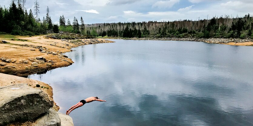 Ein Mann springt von einem Felsen in den Oderteich.