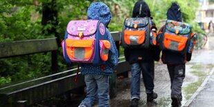 Kinder bei Regenwetter auf dem Weg zur Schule