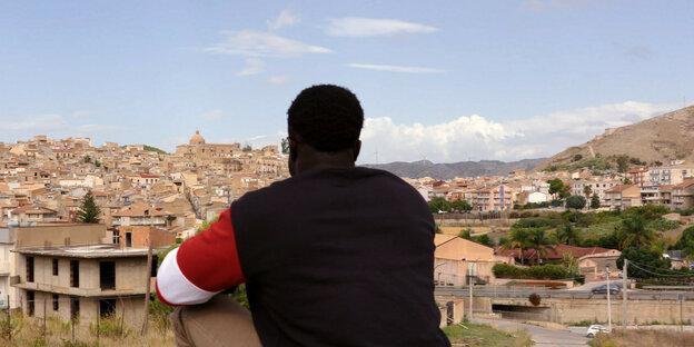 Ein Migrant blickt auf die Stadt Siculiana von einem Hügel