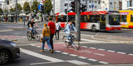 Straßenkreuzung mit Fußgängern, Radfahrern, Bus, Straßenbahn und Auto
