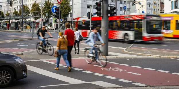 Straßenkreuzung mit Fußgängern, Radfahrern, Bus, Straßenbahn und Auto