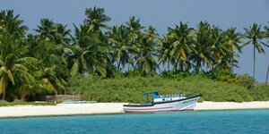Strand von Bangaram Island mit Palmen und Motorboot