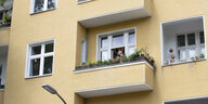 Frau steht auf dem Balkon eines gelb gestrichenen Hauses
