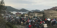 Menschenmassen, die per Motorrad, Auto oder zu Fuß die Stadt Goma verlassen.