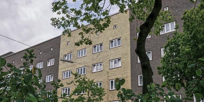 Nebeneinander stehenden Mehrfamilienhäuser aus Backstein. Eines ist vergoldet