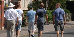 Fünf Männer auf einer Straße von hinten fotografiert