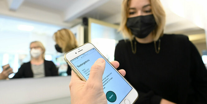 Ein Kundin zeigt bei einem Friseur auf ihrem Handy das Ergebnis eines Corona-Schnelltests