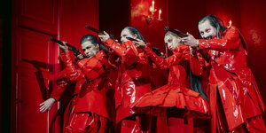 Ausschnitt aus Theaterstück "Die Jagdgesellschaft" : Vier Schauspieler in roten Lackanzügen zielen mit Gewehren
