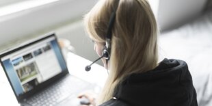 Frau sitzt im Büro vor dem Rechner und trägt ein Headset