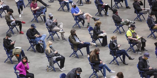 Menschen auf Stühlen im 2 Meter-Abstand warten auf ihre Impfung in Seattle, USA