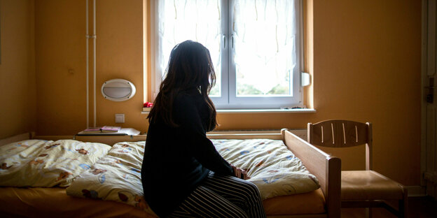 Eine Frau sitzt in einem Frauenhaus auf einem Bett